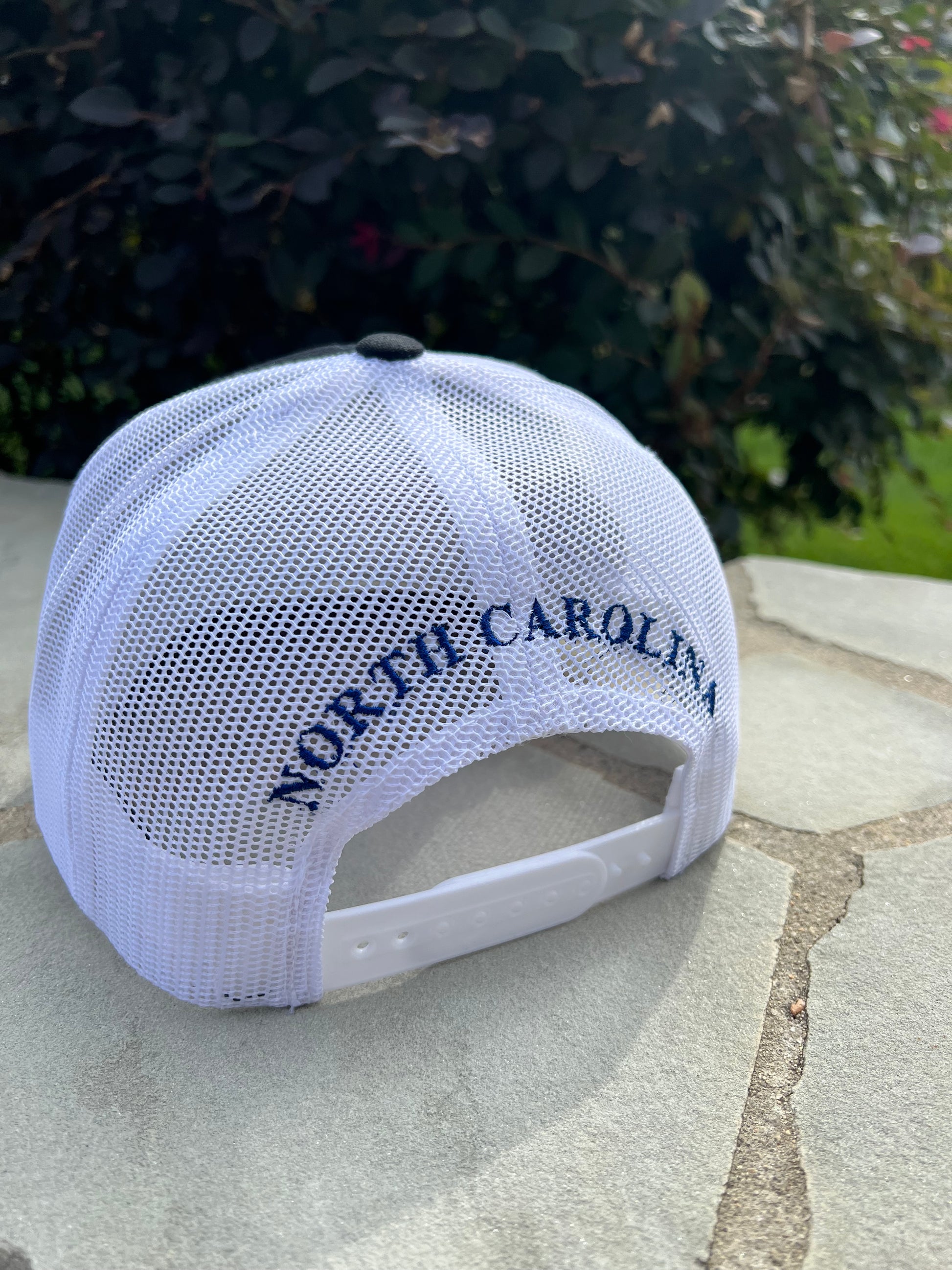 Back view of the hat. White mesh with the words North Carolina written on the back in blue lettering